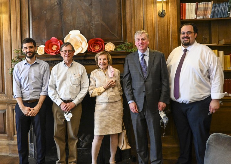 ISAW graduates posing together in front of a fireplace along with ISAW's founder, director, and director emeritus