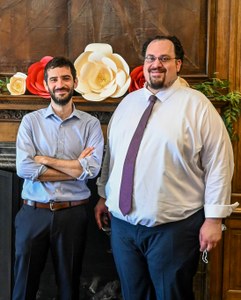 Two ISAW graduates posing together in front of a fireplace