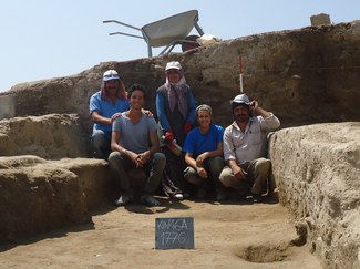 photograph showing five members of the excavation team posed together in a trench