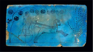 Faience tablet depicting man riding on horse-drawn chariot