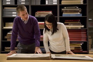 Two students look at a folio volume in the ISAW Library.