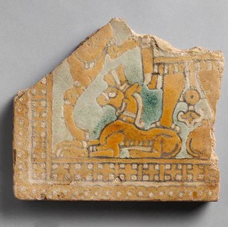 Fragmentary tile with a genie standing on a bull. The tile is orangish- yellow in color