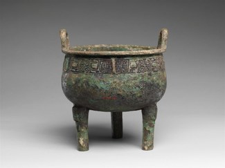 Bronze footed vessel with handles and a decorated band near rim.