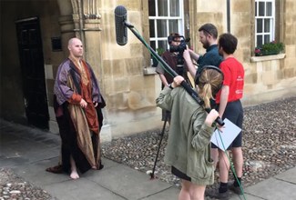 A behind the scenes shot of the actors in costume and the film crew