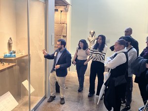 Guide points to case of object in gallery at museum