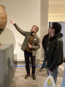 Guide points to large ceremonial pottery in gallery at museum