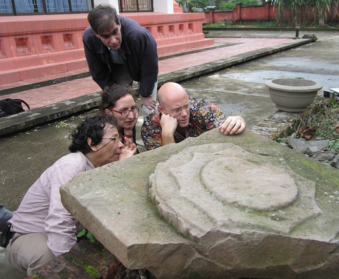 Five people looking at an inscribed stone object.