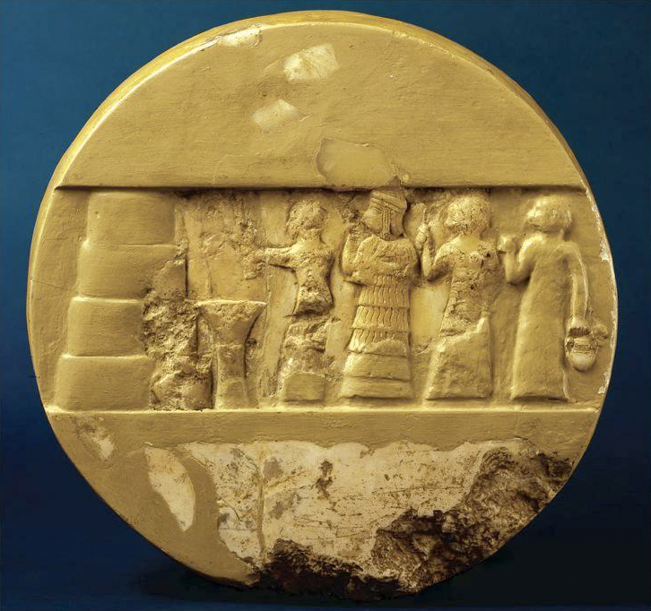 On a smooth, circular stone or ceramic object, a rectangular band across the middle shows four human figures lined up in front of altar and an object made of four large rounded blocks stacked, each slightly smaller than the one below. The disc is damaged at the bottom and in the figural area. It is coated with a yellow pigment or glaze, which has worn off in some areas.