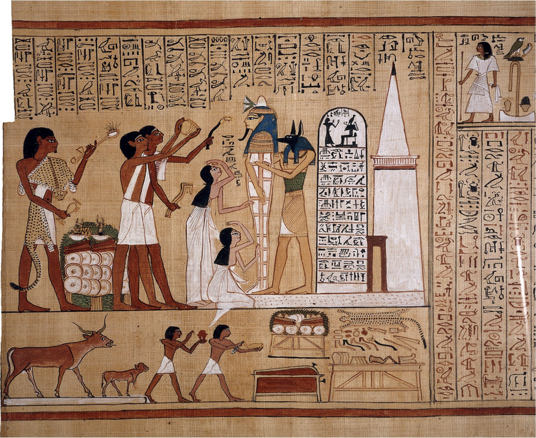 In a colorful Egyptian illustrated papyrus, a jackal-headed humanoid figure holds up a mummy in a standing position while female mourners gesture in front and, behdin them, male figures raise various objects to the mummy's head level. Vertical rows of hieroglyphic text, as well as other illustrations, surround the main image.