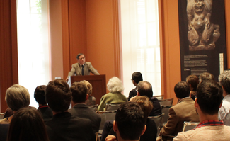 A man addresses a lecture hall from a podium.