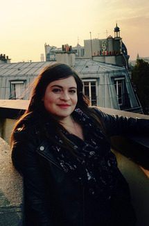 Portrait of Irene Soto with a roofline and sky behind.