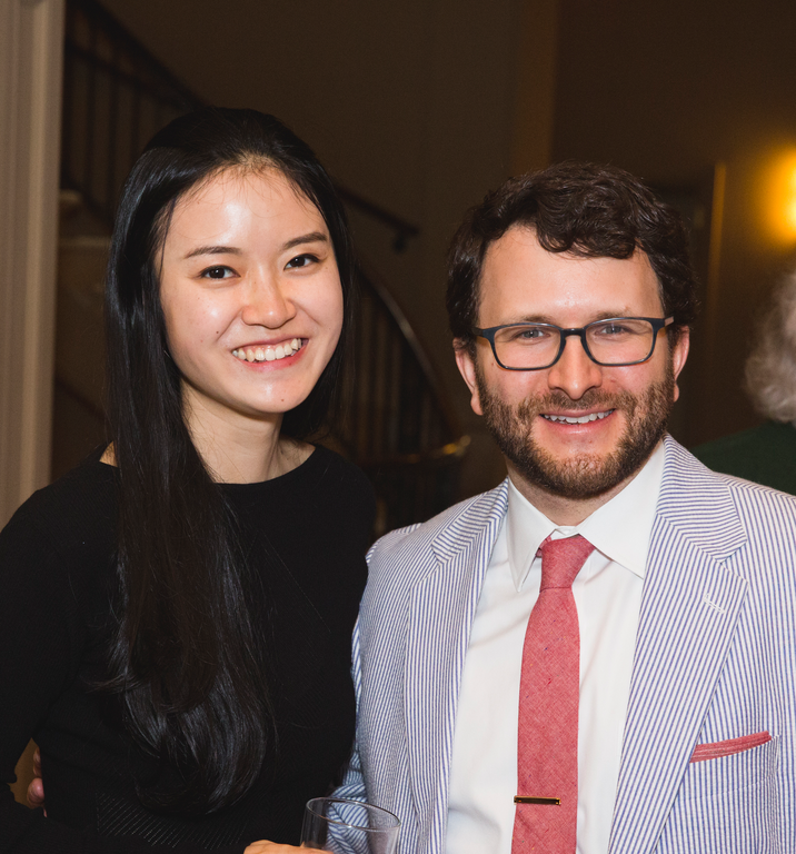 Two people pose for a photo in front of an open doorway.