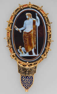 An oval-shaped black, brown, and white cameo in an elaborate gold and enamel frame, depicts a bearded male figure holding a spear and a thunderbolt with an eagle standing near his feet.