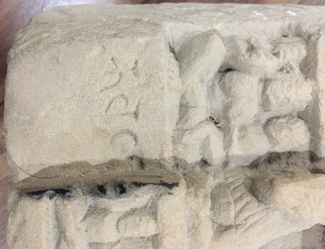 Detail photograph of a stone sculpture showing some inscribed characters.