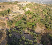 Excavations in progress can be seen in the each of the labeled sectors (A in the foreground, B in the middle distance, and C at the top of the hill). The acropolis hill otherwise features a mixture of open areas and paths of sandy soil, green shrubs and small trees.