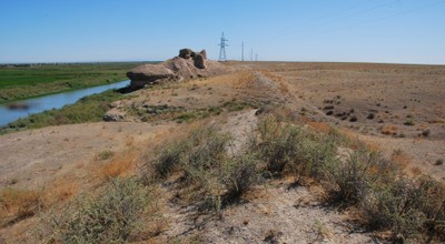 In the eastern part of the oasis. In the foreground the remains of the wall proper (today preserved as a slightly elevated earth wall), in the background a watchtower. To the left the oasis (with irrigated fields), to the right steppelands. Photo by Soeren Stark, all rights reserved.